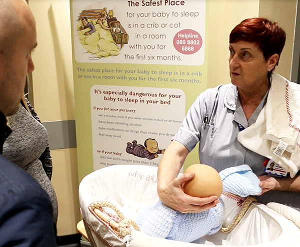 Midwifery assistant demonstrating safer sleeping