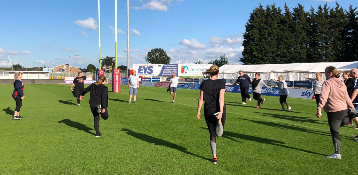 People standing in a group stretching on a rugby field