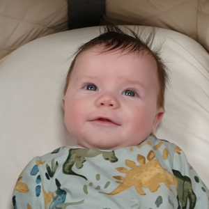 Baby Oscar smiling, laying in his pram
