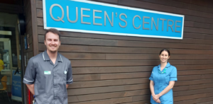 Specialist nurses standing alongside signage outside the Queen's Centre