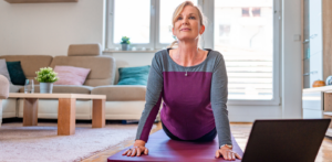 Older woman exercising at home in front of a laptop