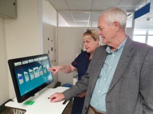 Nurse showing visitor standing in front of RITA screen demonstrating how it works