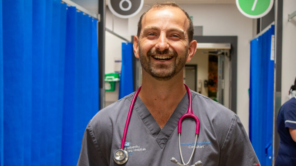 Dr Austin Smithies, smiling and standing in the emergency department.