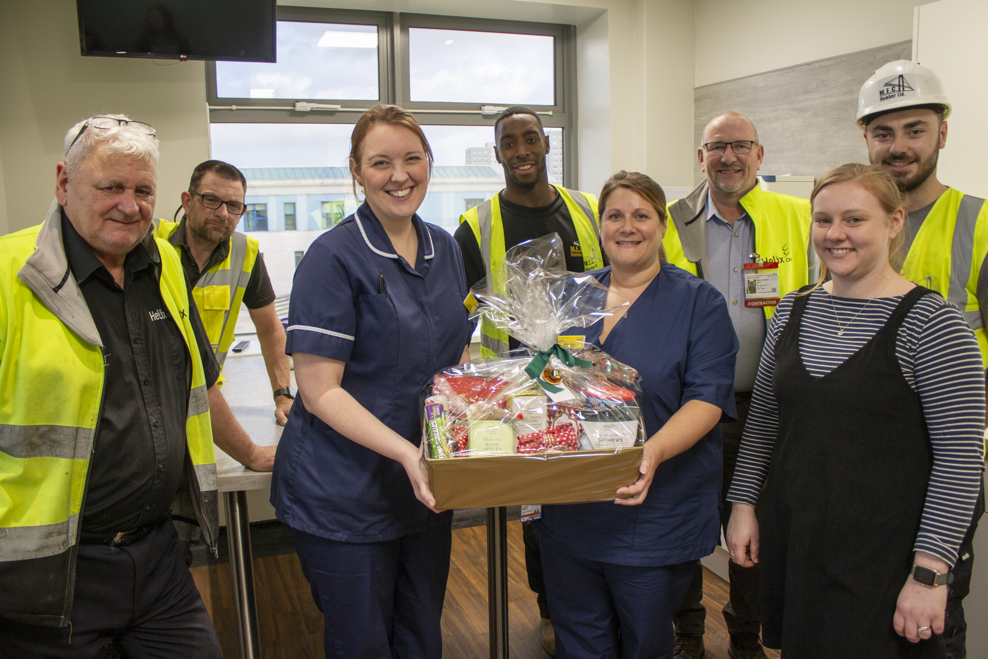 Construction staff and NICU staff receiving a gift hamper in the newly refurbished parents room