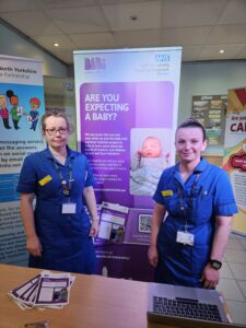 Sarah and Eloise, research nurses standing at a table seeking to recruit study participants