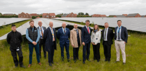 Group of people standing in a field in front of solar panels