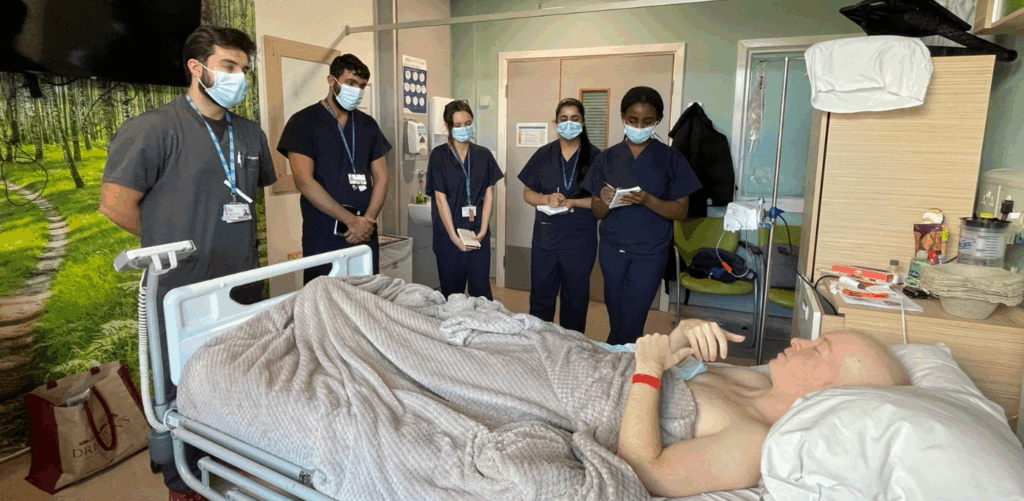 Man in hospital bed surrounded by trainee doctors