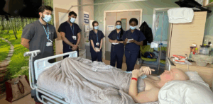 Man in hospital bed surrounded by trainee doctors