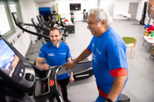 Activity instructor guiding a man on a treadmill