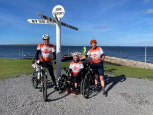 Adrian, Dr Smithson and Sarah Johnson on their bikes and trike at the John O'Groats landmark