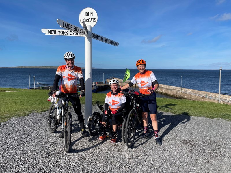 Adrian, Dr Smithson and Sarah Johnson on their bikes and trike at the John O'Groats landmark