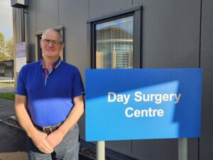 A man stood next to a sign saying "Day Surgery Centre"