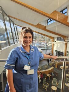 Zowie in nursing uniform standing on a balcony overlooking the Queen's Centre reception area